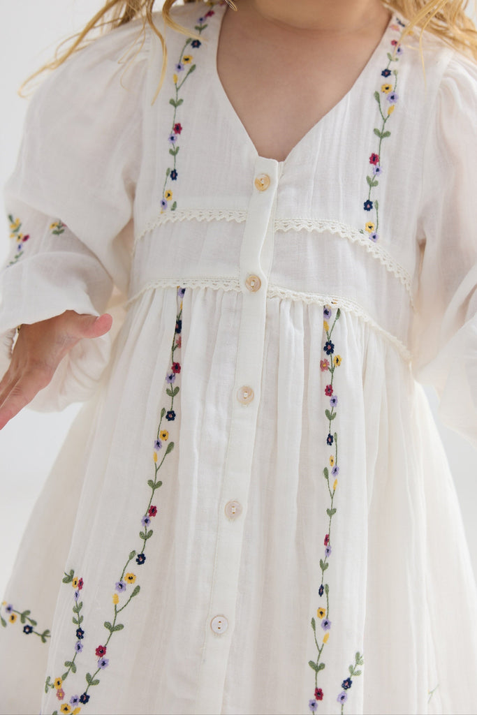 White dress with colorful embroidery on a child against a white background
